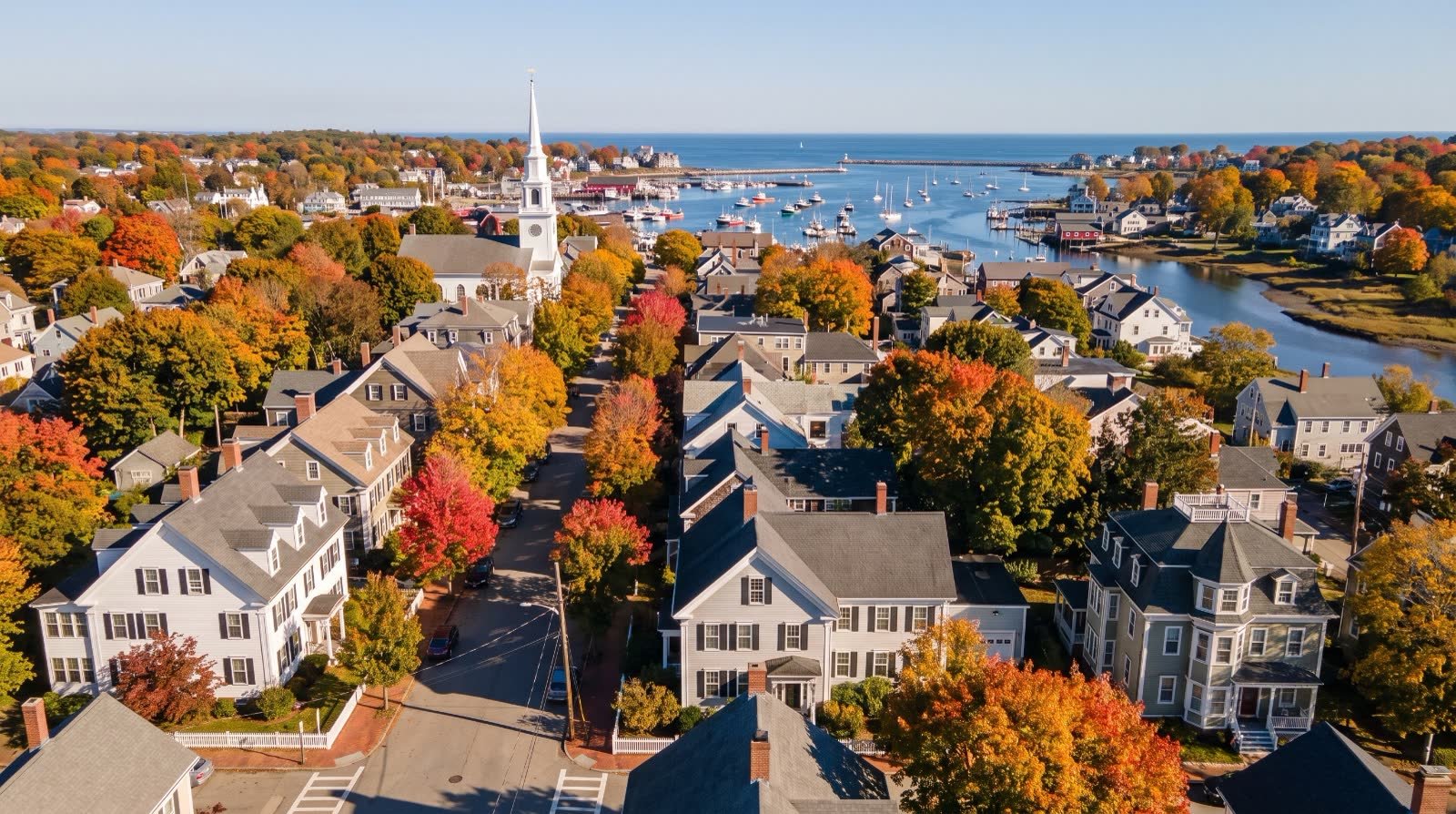 Aerial illustration of a New England coastal town in autumn with a white church steeple and harbor